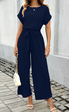 Woman wearing a navy blue jumpsuit with a white background